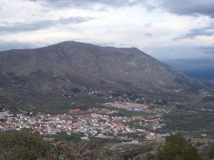 Vista general de Bustarviejo con Cabeza Cervunal detrás y el Cancho de Mondalindo soresaliendo en la ladera, a la derecha.