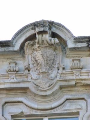 Escudo Real de España esculpido sobre el balcón principal en el eje del cuerpo central de la fachada de la Real Fábrica de Paños.