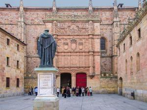 Fachada principal del Edificio histórico de la Universidad de Salamanca y estatua de Fray Luis de León de espaldas