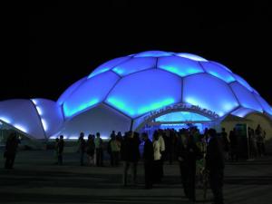 La Cúpula del Milenio iluminada por la noche, un edificio claramente inspirado por las corrientes arquitectónicas contemporáneas del siglo XXI